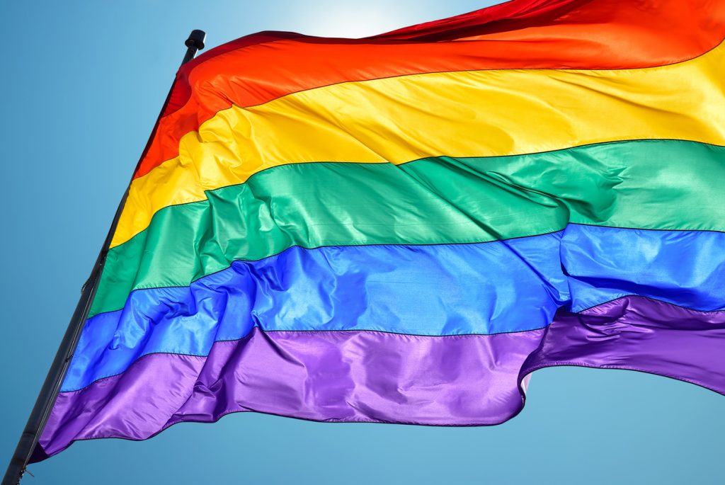 Rainbow flag on clear sky symbol of tolerance and acceptance - HospitalityLawyer.com®