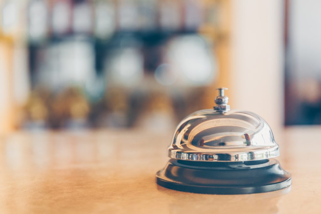 Ring bell for staff calling on the stand. Reception and bar background. Holiday and travel concept - HospitalityLawyer.com®