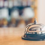 Ring bell for staff calling on the stand. Reception and bar background. Holiday and travel concept - HospitalityLawyer.com®