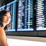 Beautiful Asian woman traveler at flight information screen - HospitalityLawyer.com®