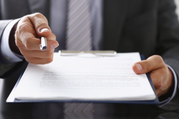 Close-up of businessman propose to sign paper, give silver pen to make deal on document. Prepared business papers for client. Business, success concept