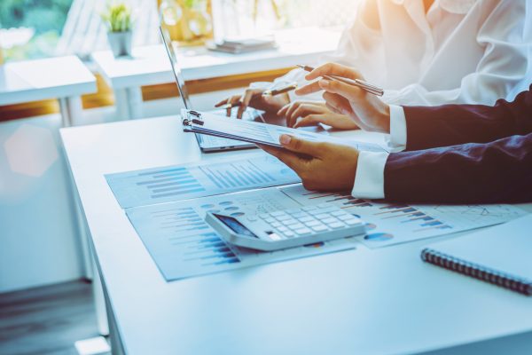 Close-up of two businesswomen calculating financial statements at a desk.