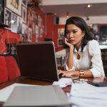Paying bills online - HospitalityLawyer.com® Pensive Asian bar owner using laptop to pay bills online