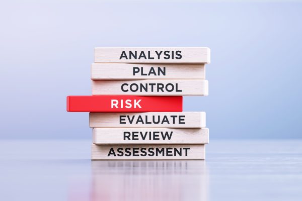 Risk management related words written wood blocks sitting on a wood surface in front of a defocused background. Risk management concept.