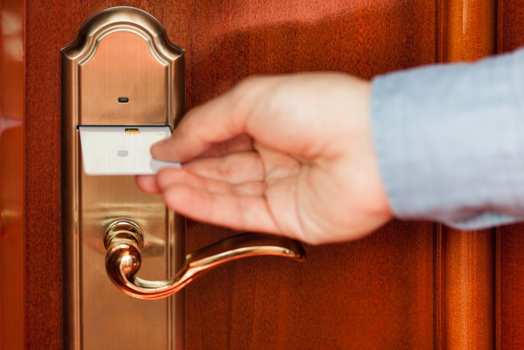 Unlocking hotel room with card key - HospitalityLawyer.com® Man using a key card to enter a hotel room.