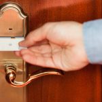Unlocking hotel room with card key - HospitalityLawyer.com® Man using a key card to enter a hotel room.