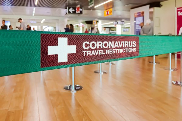 Green ribbon barrier inside an airport with the warning of travel restrictions due to the spread of the dangerous Coronavirus