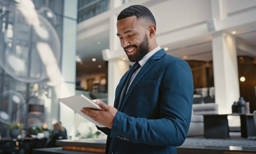 Businessman, digital tablet or strategy planning in hotel conference lobby or airport travel lounge. Happy smile, corporate worker or technology app to budget company finance or schedule target goals