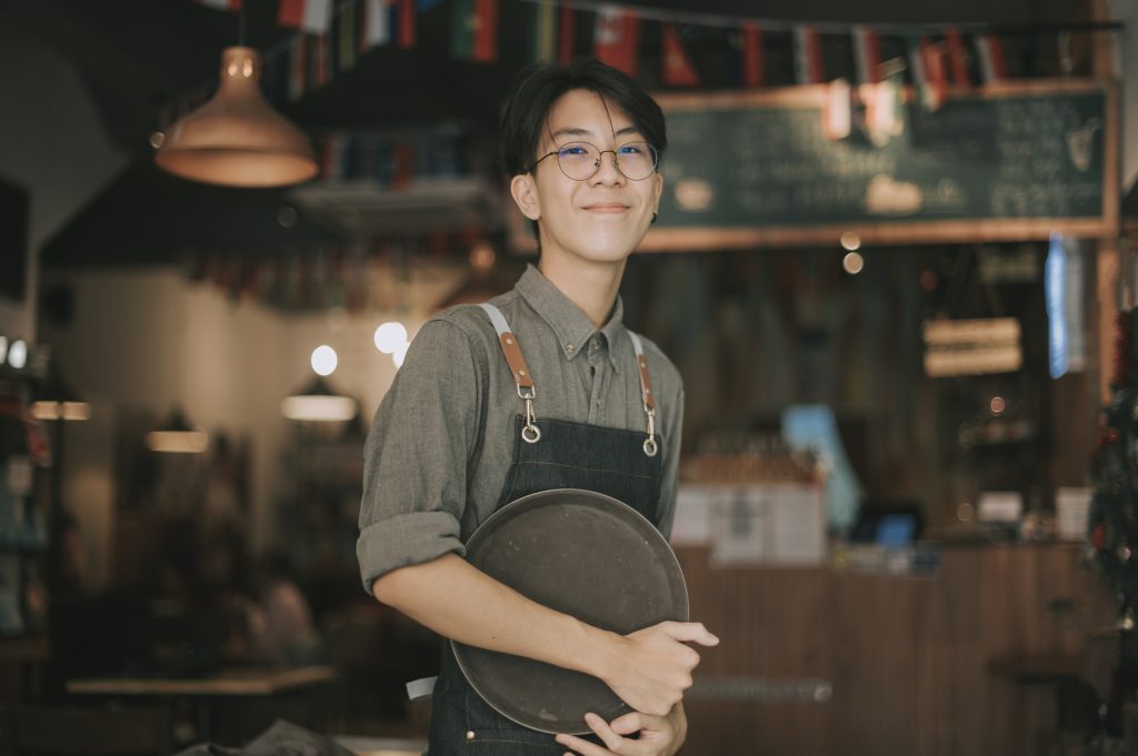 asian chinese teenage boy waiter looking at camera smiling work at cafe opening - HospitalityLawyer.com®