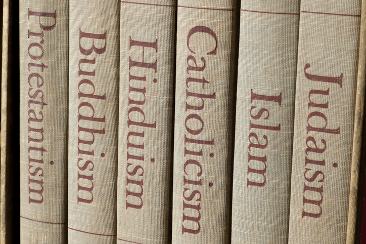 Book spines listing major world religions - Judaism, Islam, Catholicism, Hinduism, Buddhism and Protestantism.