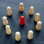 Circle from wooden figures and red figure. Discrimination or harassment concept.