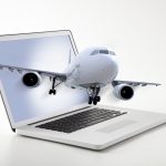 Passenger plane coming out of laptop screen symbolizing online ticketing