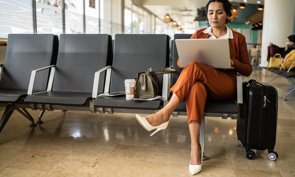 Businesswoman using laptop in the departure area at airport