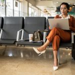 Businesswoman using laptop in the departure area at airport - HospitalityLawyer.com® Businesswoman using laptop in the departure area at airport