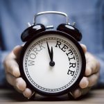 Businessman holding black alarm clock with clockwise countdown from work to retirement - HospitalityLawyer.com®