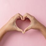 Heart shape created from young womans hands on pastel pink background - HospitalityLawyer.com®