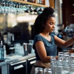 waitress pouring beer draft beer while working at bar counter - HospitalityLawyer.com®