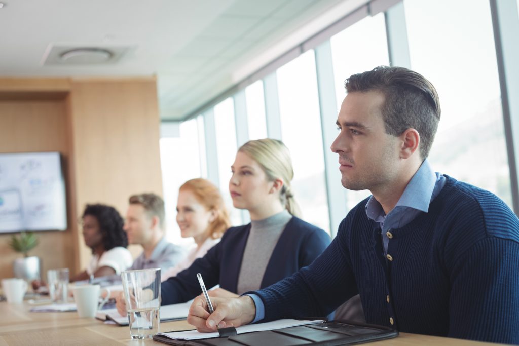 Concentrated business people sitting at conference table during meeting - HospitalityLawyer.com®