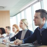 Concentrated business people sitting at conference table during meeting - HospitalityLawyer.com®