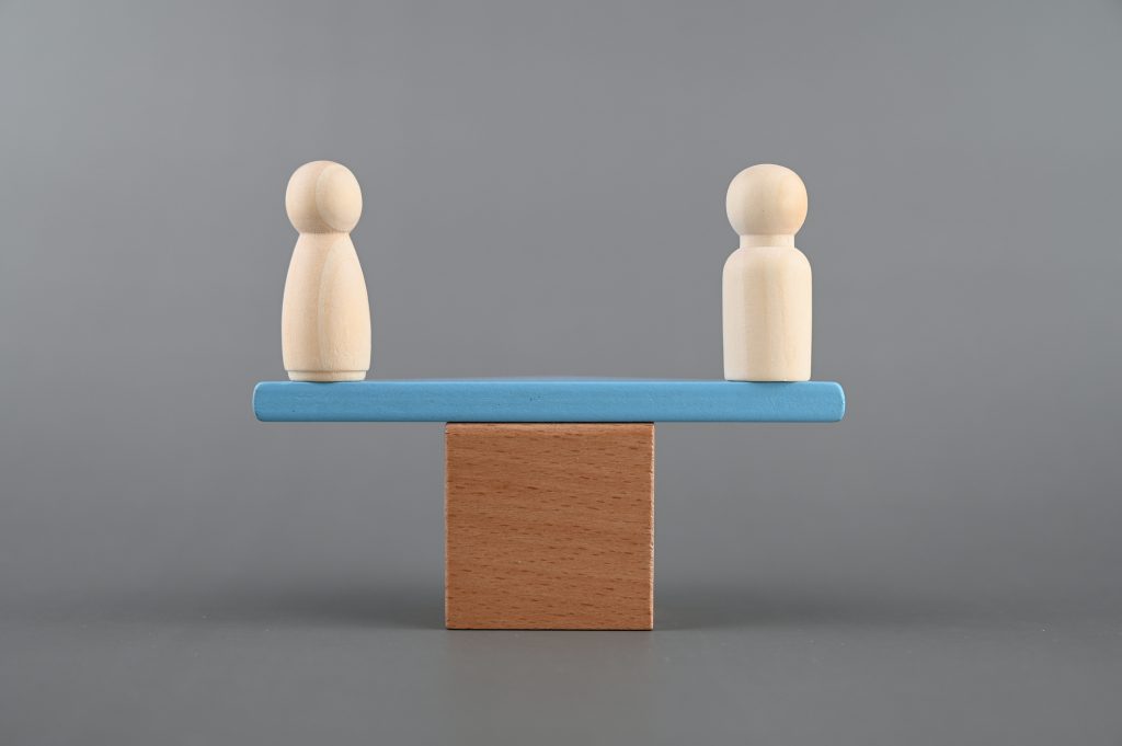 Man and woman figure on a scale Gender equality concept - HospitalityLawyer.com®