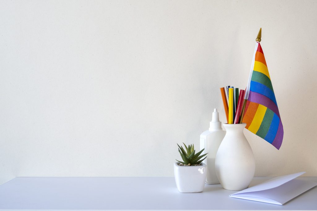 LGBT office desk with rainbow flag and stationery blank wall with space for text - HospitalityLawyer.com®