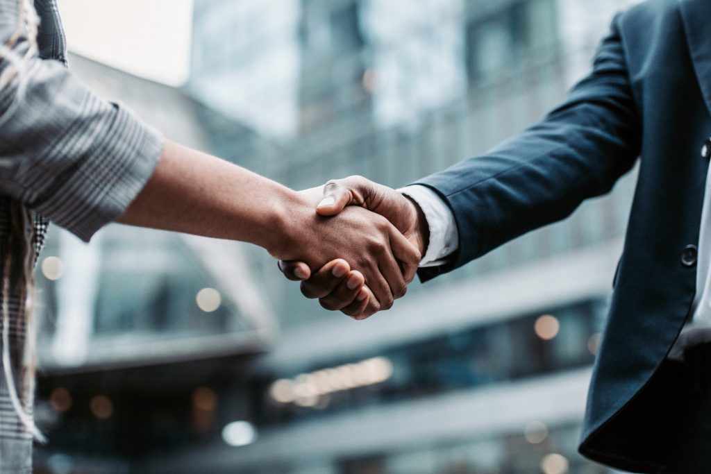 Meeting success Two business persons shaking hands standing outside - HospitalityLawyer.com®