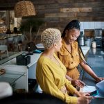 Small business owners talking and discussing the performance of their coffee shop. - HospitalityLawyer.com®