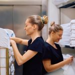 Happy maids working in hotel laundry room - HospitalityLawyer.com®