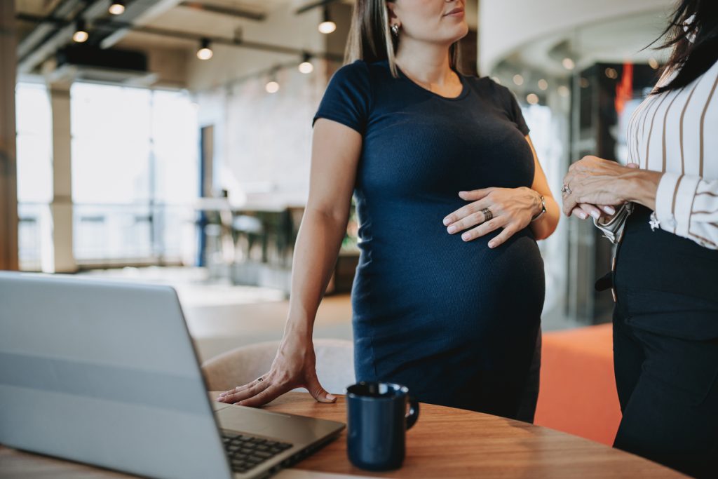 pregnant businesswoman talking to coworker - HospitalityLawyer.com®