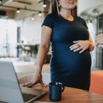 pregnant businesswoman talking to coworker - HospitalityLawyer.com®