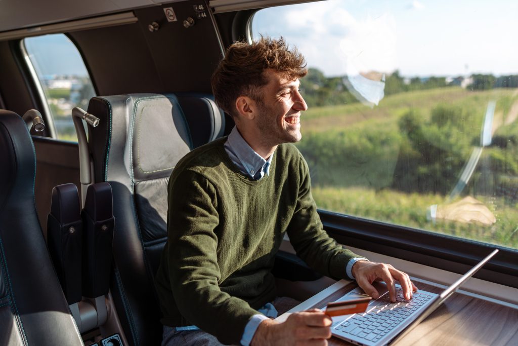 Young man with a credit card and a laptop E commerce on the go - HospitalityLawyer.com®