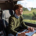 Young man with a credit card and a laptop E commerce on the go - HospitalityLawyer.com®
