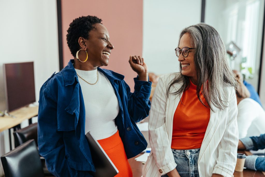 Creative colleagues laughing in a vibrant and colorful workplace - HospitalityLawyer.com®