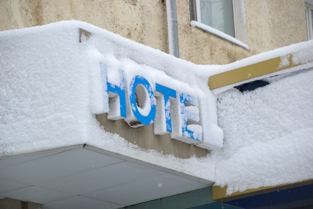 Hotel entrance sign covered in fresh snow after heavy snowfall winter scenery - HospitalityLawyer.com®